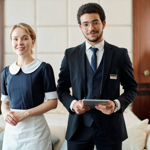 Young successful staff of luxurious five star hotel standing in room